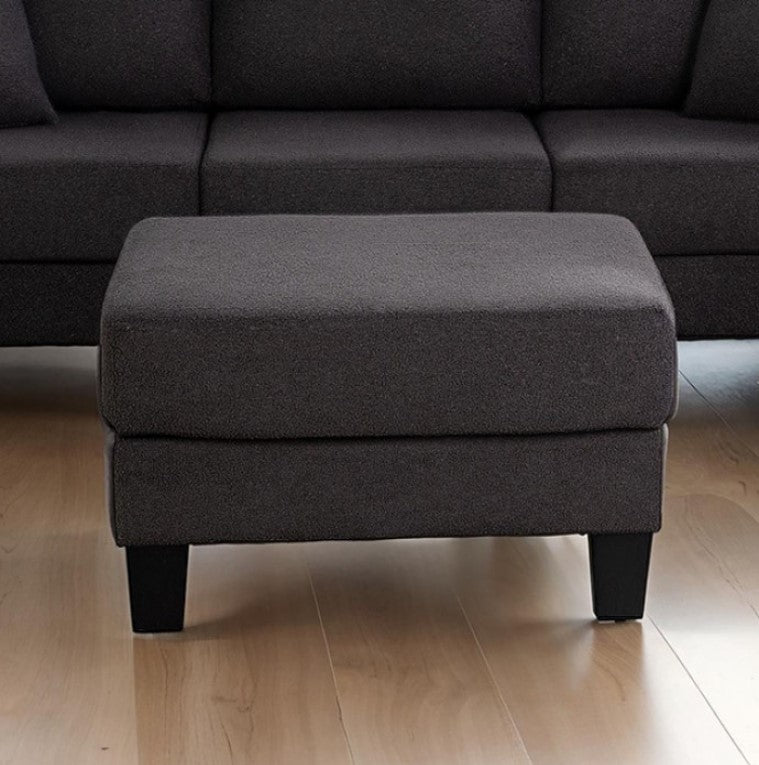 Dark gray ottoman in front of a dark gray sectional sofa on a wooden floor.