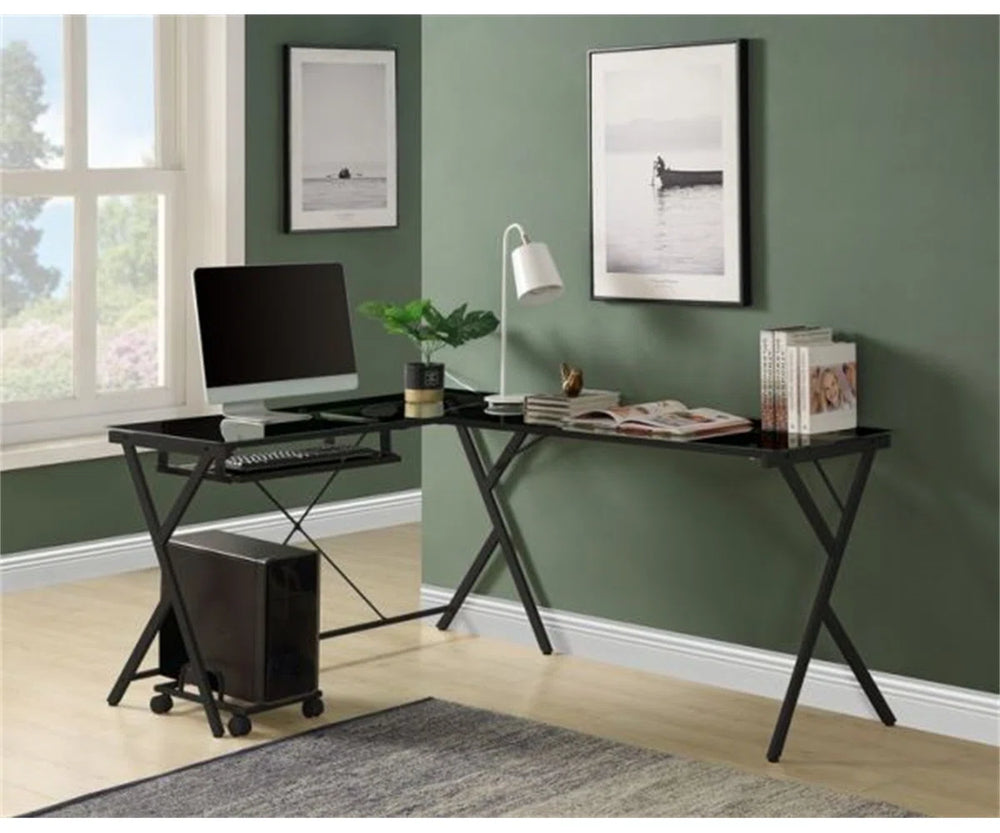Modern home office setup with a black L-shaped desk, computer monitor, keyboard, and decor items against a green wall.