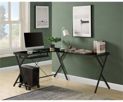 Modern home office setup with a black L-shaped desk, computer monitor, keyboard, and decor items against a green wall.