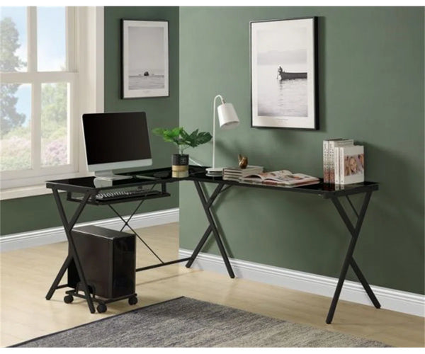 Modern home office setup with a black L-shaped desk, computer monitor, keyboard, and decor items against a green wall.