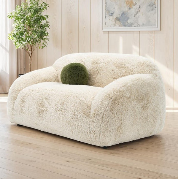 White fluffy armchair with a green spherical object on a wooden floor.