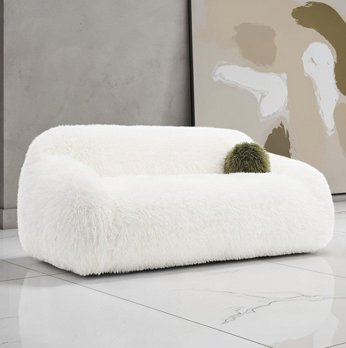 Dareen Contemporary White Faux Fur Sofa with Ball Pillows White fluffy chair with a green cushion in a modern room.