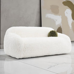 Dareen Contemporary White Faux Fur Sofa with Ball Pillows White fluffy chair with a green cushion in a modern room.