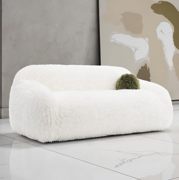 Dareen Contemporary White Faux Fur Sofa with Ball Pillows White fluffy chair with a green cushion in a modern room.