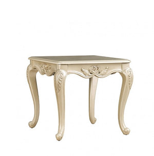 Decorative beige side table with intricate carvings on a white background