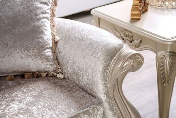 Darian Diamond Tufted Traditional Style Sofa Off White Luxurious off white upholstered chair with ornate armrests and a decorative table in the background.