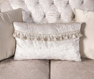 Decorative pillow with tassels on a textured wall and sofa background