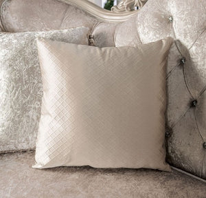 Quilted beige pillow on a decorative sofa with intricate patterns