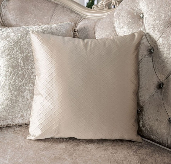 Quilted beige pillow on a decorative sofa with intricate patterns