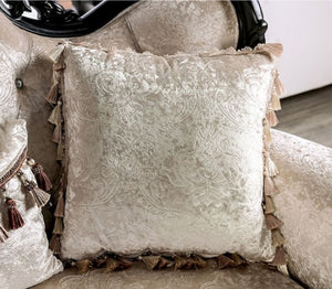 Decorative pillow with intricate patterns and tassels on a textured surface