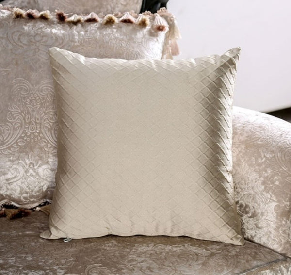 Quilted beige pillow on a textured surface
