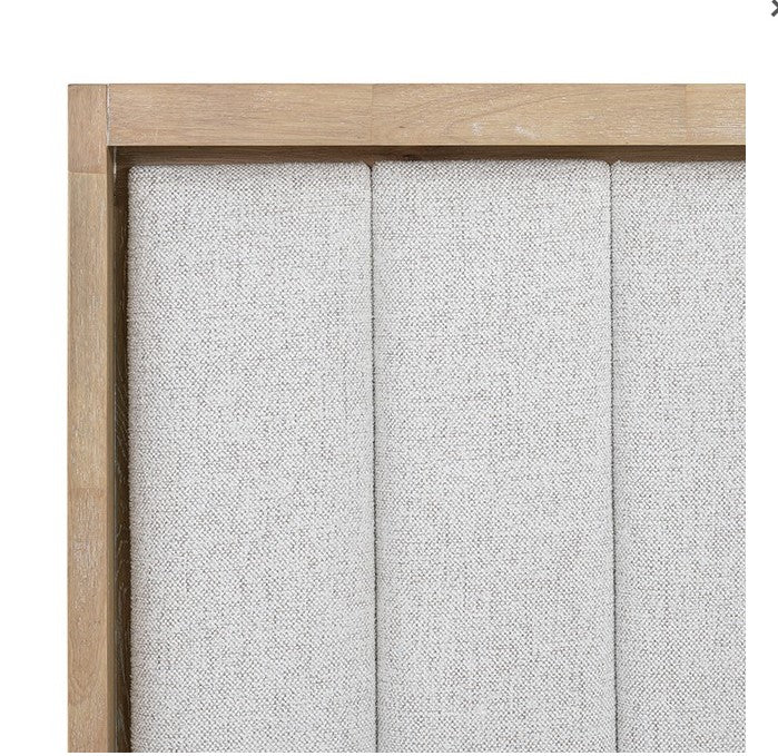 Delmar Natural Finish Upholstered Bed Neatly made bed with wooden headboard in a bedroom setting.