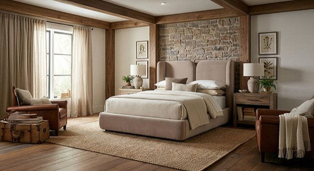 Denvers High Headboard Fabric Bed Beige upholstered bed in a bedroom with stone wall and wooden floor.