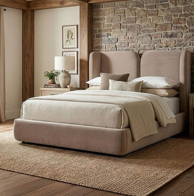 Denvers High Headboard Fabric Bed Beige upholstered bed in a bedroom with stone wall and wooden floor.