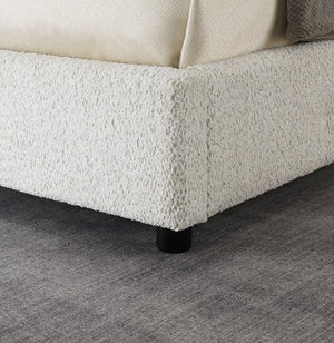 Close-up of a textured bed frame with a soft finish on a gray floor.