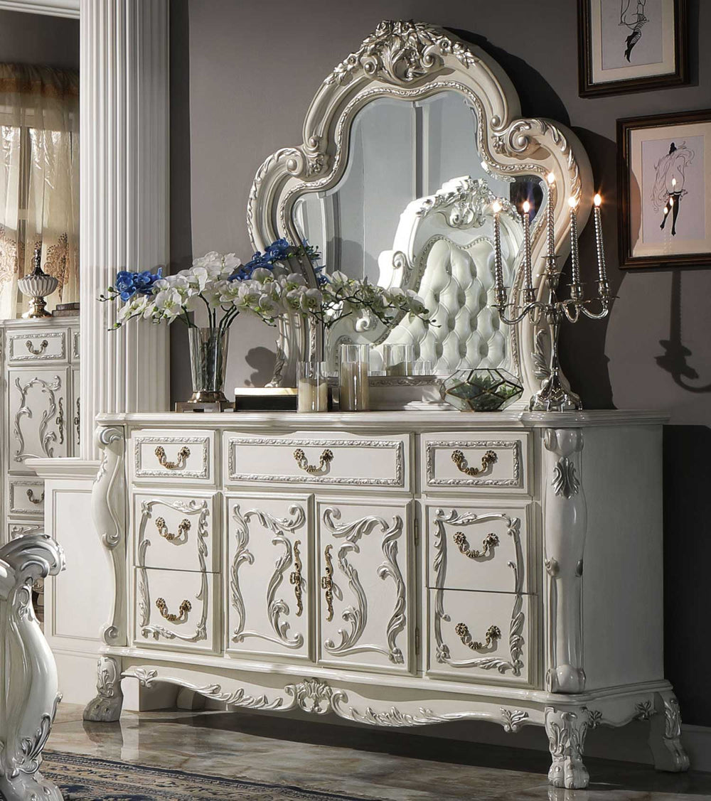 Dresden Bone White Traditional Style Dresser An ornate white carved wooden dresser with a large matching arched mirror, styled in a luxurious bedroom setting with floral arrangements and a candelabra.