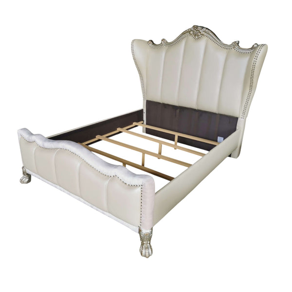 Dresden Bone White Traditional Style Fully Upholstered Bed An elegant upholstered bed frame with a tall wingback headboard and footboard, finished in cream faux leather with silver nailhead trim and ornate silver legs, shown on a white background.