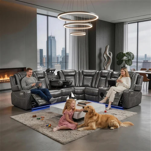 Eloise Power Gray Recliner Sectional Sofa LED Multi Color Lights A large black leather sectional sofa with recliners is shown in a modern living room with a man, woman, and dog interacting on a rug in front of it. The room has large windows with a city skyline view, a hanging ring chandelier, and a fireplace.