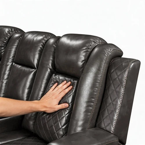 Eloise Power Gray Recliner Sectional Sofa LED Multi Color Lights Close-up of a black leather recliner chair with a hand pressing into the quilted backrest cushion to show the material texture and support.