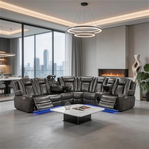Eloise Power Gray Recliner Sectional Sofa LED Multi Color Lights A large black leather sectional sofa with multiple reclining seats and built-in cup holders, shown in a modern living room with a fireplace, city view windows, and a round ring chandelier.