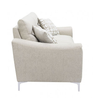 Estrella Light Taupe Brown Slope Flair Arm Sofa A light beige upholstered loveseat with two accent pillows, one in a light gray and white geometric pattern, shown from a three-quarter angle on a white background.