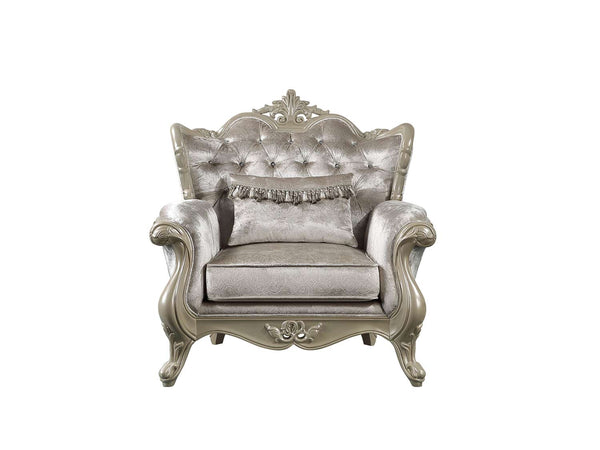 Ethaan Button Tufted Traditional Fabric Chair A single ornate baroque-style armchair upholstered in shimmering champagne-gray velvet, featuring a tufted backrest, decorative carved frame, and a matching fringed accent pillow, shown against a plain white background.