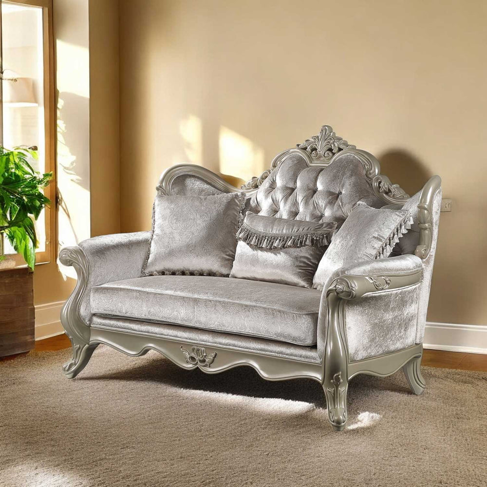 Ethaan Button Tufted Traditional Fabric Loveseat Decorative silver sofa with intricate designs in a room with beige walls and a plant.