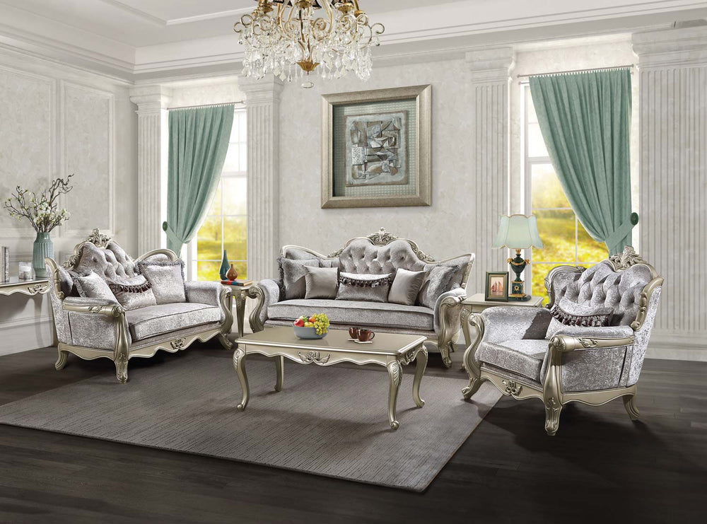 Ethaan Button Tufted Traditional Fabric Sofa A luxury French-style living room furniture set featuring a tufted sofa, two matching armchairs, and a carved coffee table, all in a silver and gray fabric with ornate silver frames, arranged on a gray rug in a grand room with green curtains.