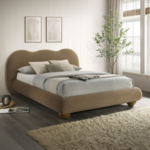 Beige upholstered bed in a bedroom with a plant and framed pictures on the wall.