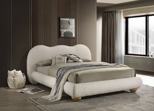 Modern bedroom with a white upholstered bed, gray bedding, and a window in the background.