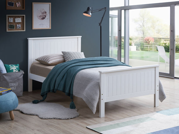 Gallow White Finish Twin Bed A white wooden single bed frame with a slatted headboard and footboard, styled in a modern bedroom with gray and teal bedding, a floor lamp, and a window looking out to a garden.