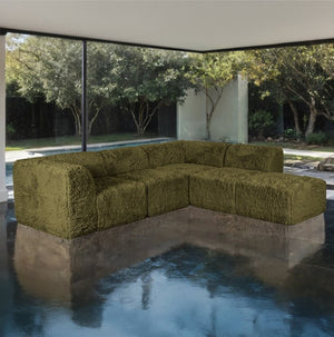 #Green Giacinto Compressed Foam Modern L-Sectional Sofa Green Finish Green textured sectional sofa in a modern outdoor setting with trees and a building in the background.