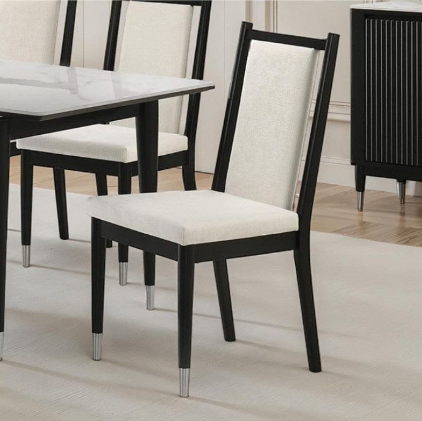 Grayson Contemporary Black White Fabric Chair Black dining chairs with cream upholstered seats and backrests, shown in a dining room setting next to a glass-top table.