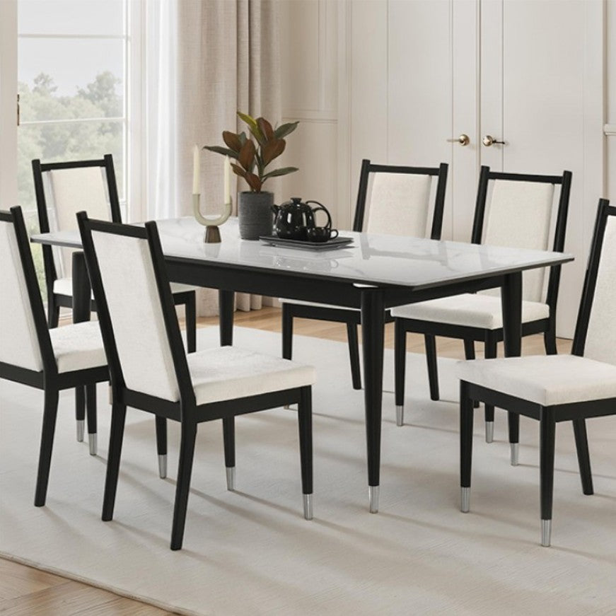 Grayson Contemporary Black White Sintered Stone Top Dining Table A 7-piece dining set featuring a rectangular table with a white marble-patterned top and black frame, surrounded by six matching chairs with black frames and off-white upholstered seats and backs, set in a bright dining room.