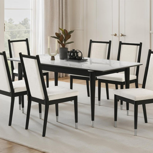 Grayson Contemporary Black White Sintered Stone Top Dining Table A 7-piece dining set featuring a rectangular table with a white marble-patterned top and black frame, surrounded by six matching chairs with black frames and off-white upholstered seats and backs, set in a bright dining room.