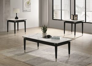 Grayson Contemporary Black White Sintered Stone Top End Table A modern living room scene showing a rectangular coffee table in the foreground, a smaller side table on the left, and another side table on the right. The tables have white marble-look tops with black frames and tapered black legs with silver metal tips.