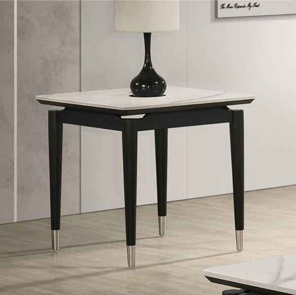 Grayson Contemporary Black White Sintered Stone Top End Table A modern black wooden side table with a white marble top and silver metal feet, styled with a black lamp in a minimalist room setting.
