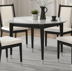 Grayson Contemporary Black White Sintered Stone Top Round Dining Table A round dining table with a white marble-look top and black legs, surrounded by five matching chairs with cream upholstered seats and black frames, set on a light gray rug in a bright dining room.