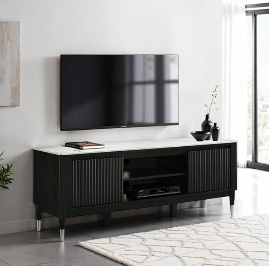 Grayson Contemporary Black White Sintered Stone Top TV Console A modern black TV stand with a white marble-look top and silver metal legs, shown in a styled living room setting with a wall-mounted TV, decorative vases, and a patterned rug.
