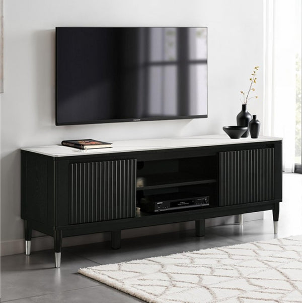 Grayson Contemporary Black White Sintered Stone Top TV Console A modern black TV stand with a white marble-look top and silver metal legs, shown in a styled living room setting with a wall-mounted TV, decorative vases, and a patterned rug.