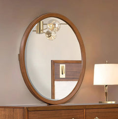 Hermin Modern Style Walnut Mirror Round wooden mirror on a dresser with a lamp in the background