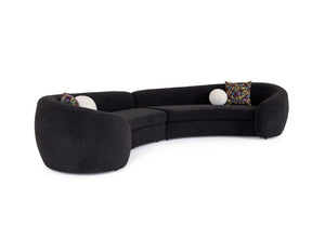 Kilmer Black Fabric Curved Modern Sectional Sofa A curved modular sectional sofa upholstered in black fabric, featuring two decorative patterned accent pillows and two white spherical side props, shown against a plain white background.