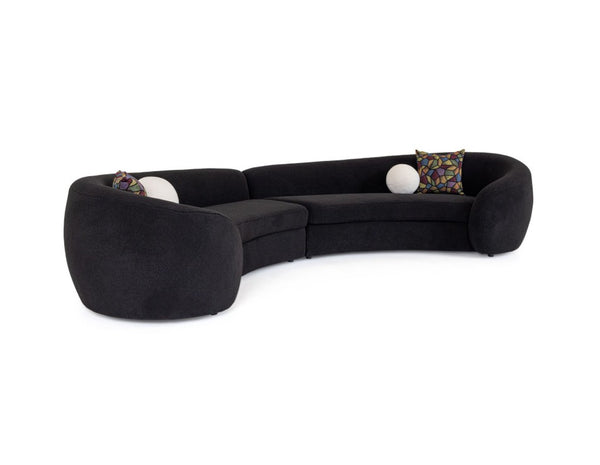 Kilmer Black Fabric Curved Modern Sectional Sofa A curved modular sectional sofa upholstered in black fabric, featuring two decorative patterned accent pillows and two white spherical side props, shown against a plain white background.