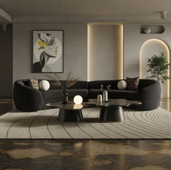 Kilmer Black Fabric Curved Modern Sectional Sofa A modern curved black sectional sofa in a styled living room, paired with round black coffee tables, a patterned rug, and a large framed abstract art print on the wall.
