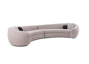 Kilmer Gray Fabric Curved Modern Sectional Sofa A curved modular upholstered sofa in a light taupe-beige fabric, featuring two black circular accent pillows and two textured light gray throw pillows, shown against a plain white background.