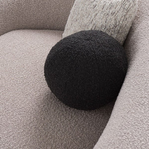 Kilmer Gray Fabric Curved Modern Sectional Sofa A round black textured throw pillow resting on a light beige boucle sofa next to a gray textured pillow.