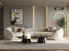 Kilmer Off White Fabric Curved Modern Sectional Sofa A modern curved white sofa in a minimalist living room setting, styled with neutral beige and brown pillows, a black coffee table, and a textured rug.