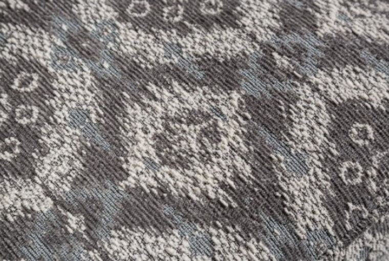 Kumar Transitional White-Gray Fabric Ottoman Patterned ottoman in a living room setting with a couch and chair.