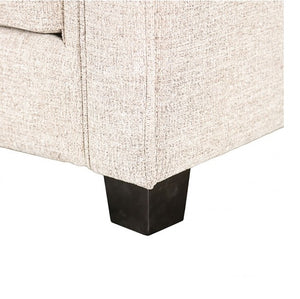 Close-up of a textured beige sofa corner with a dark wooden leg 
