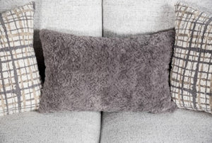 Gray textured pillow on a sofa with plaid-patterned pillows